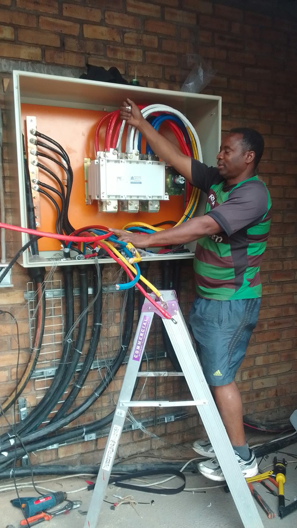 Amos C., Erga's electrician, wiring a distribution board